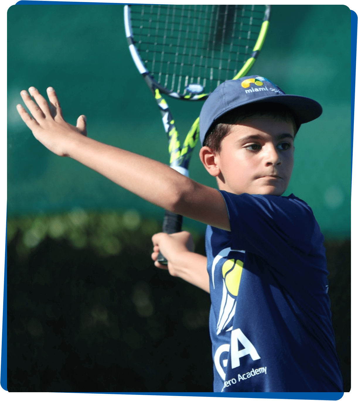 Young boy playing tennis, focused on his shot.