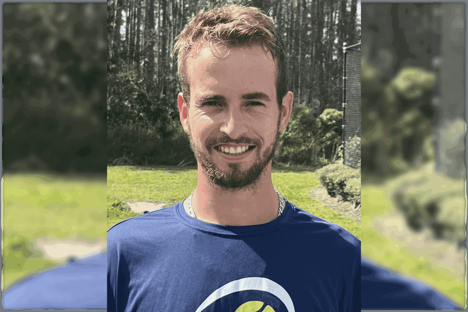 Smiling man outdoors in a casual blue shirt.