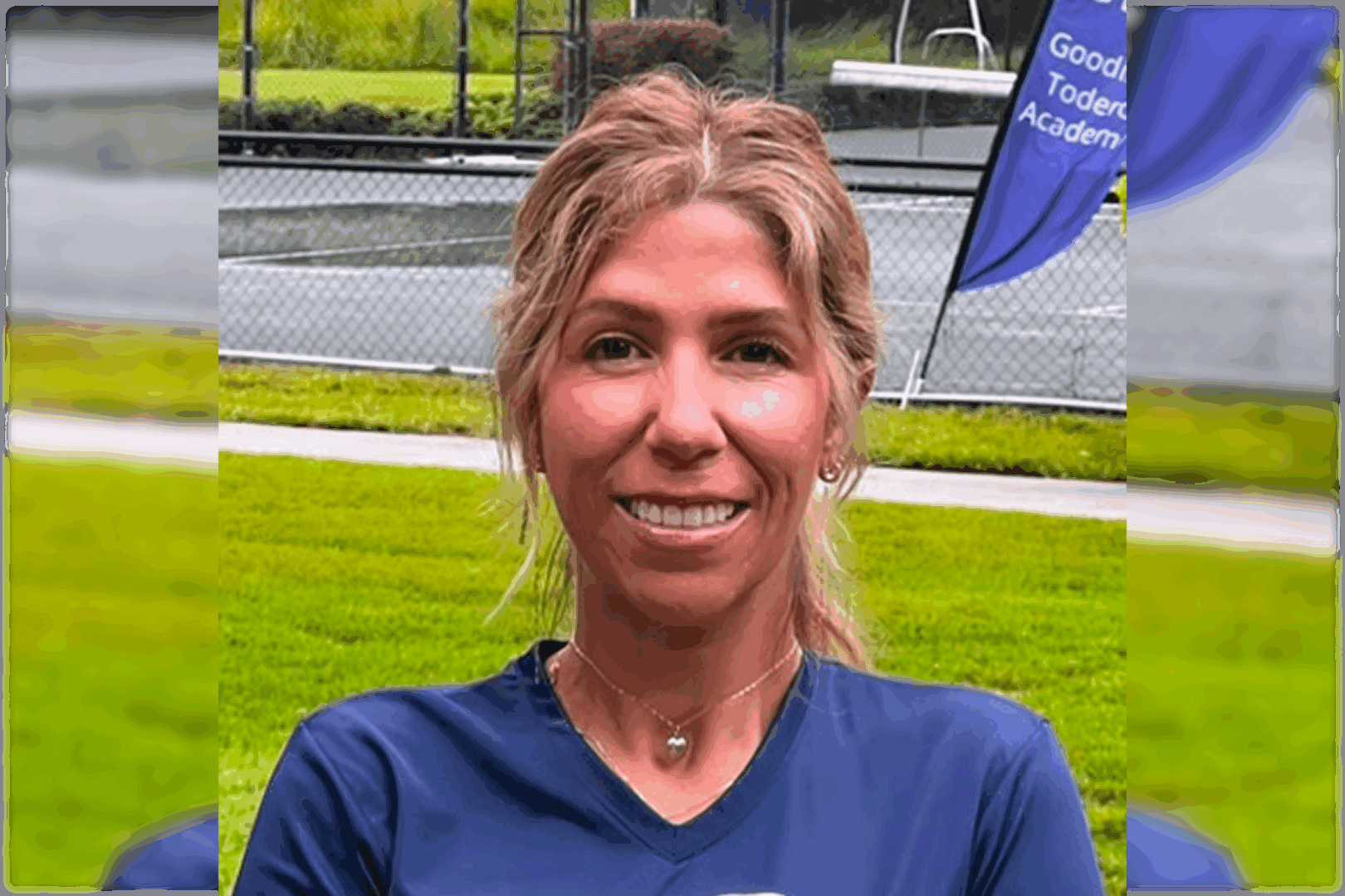 Smiling woman outdoors in a blue shirt with green grass background.