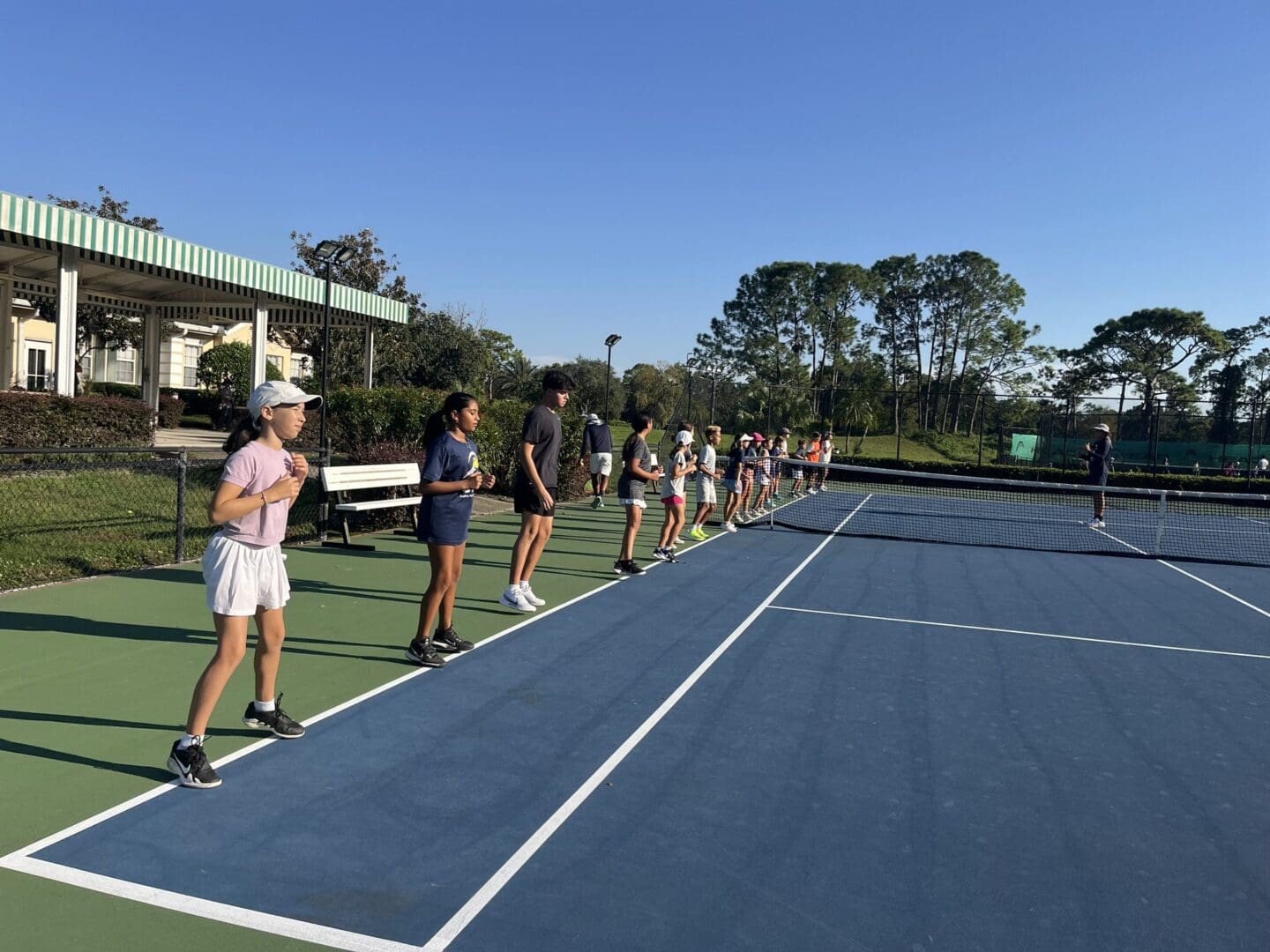 Young girls lined up on a tennis court, preparing to play.