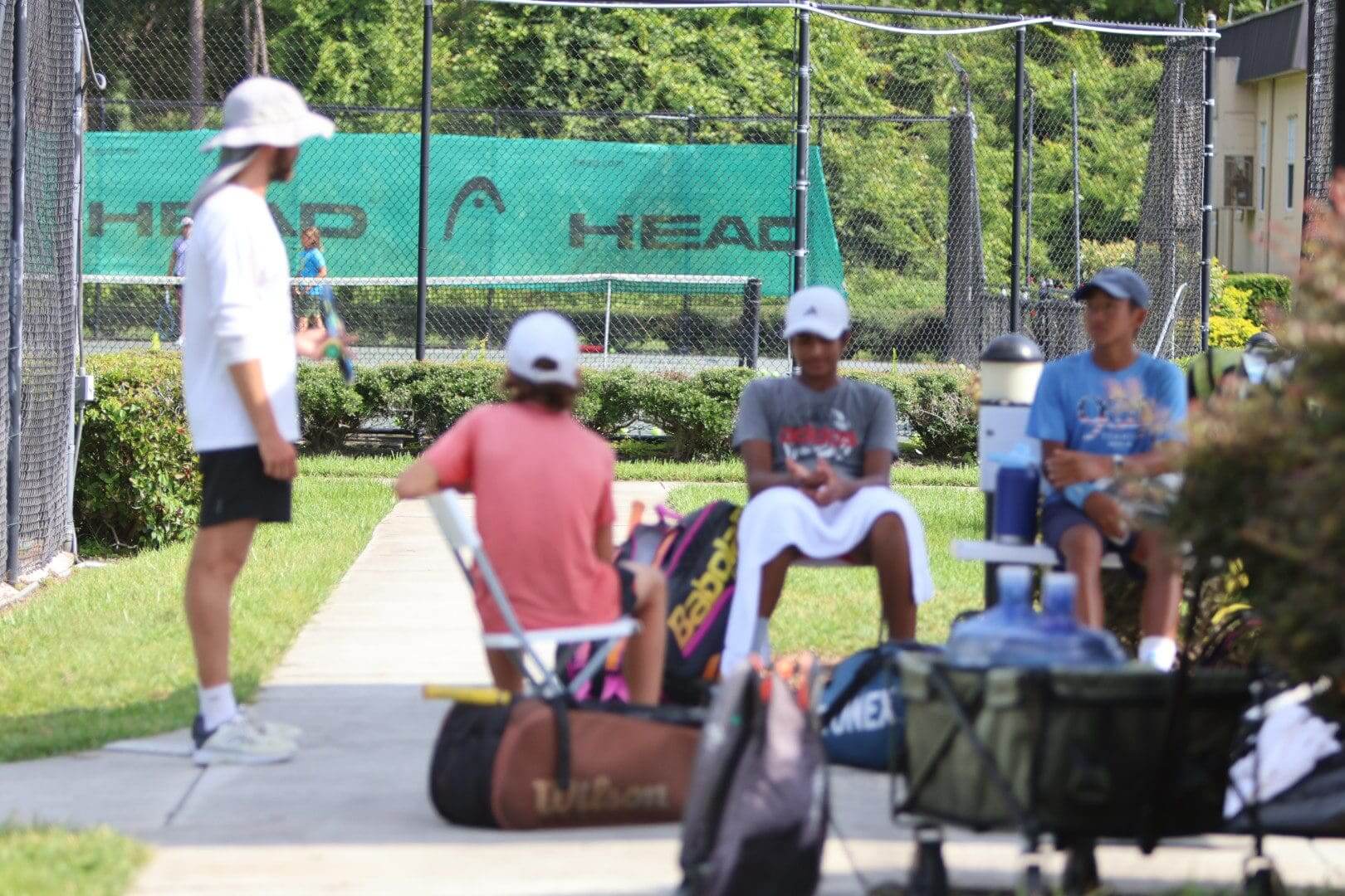 Group of boys preparing for a tennis match outdoors on a sunny day.