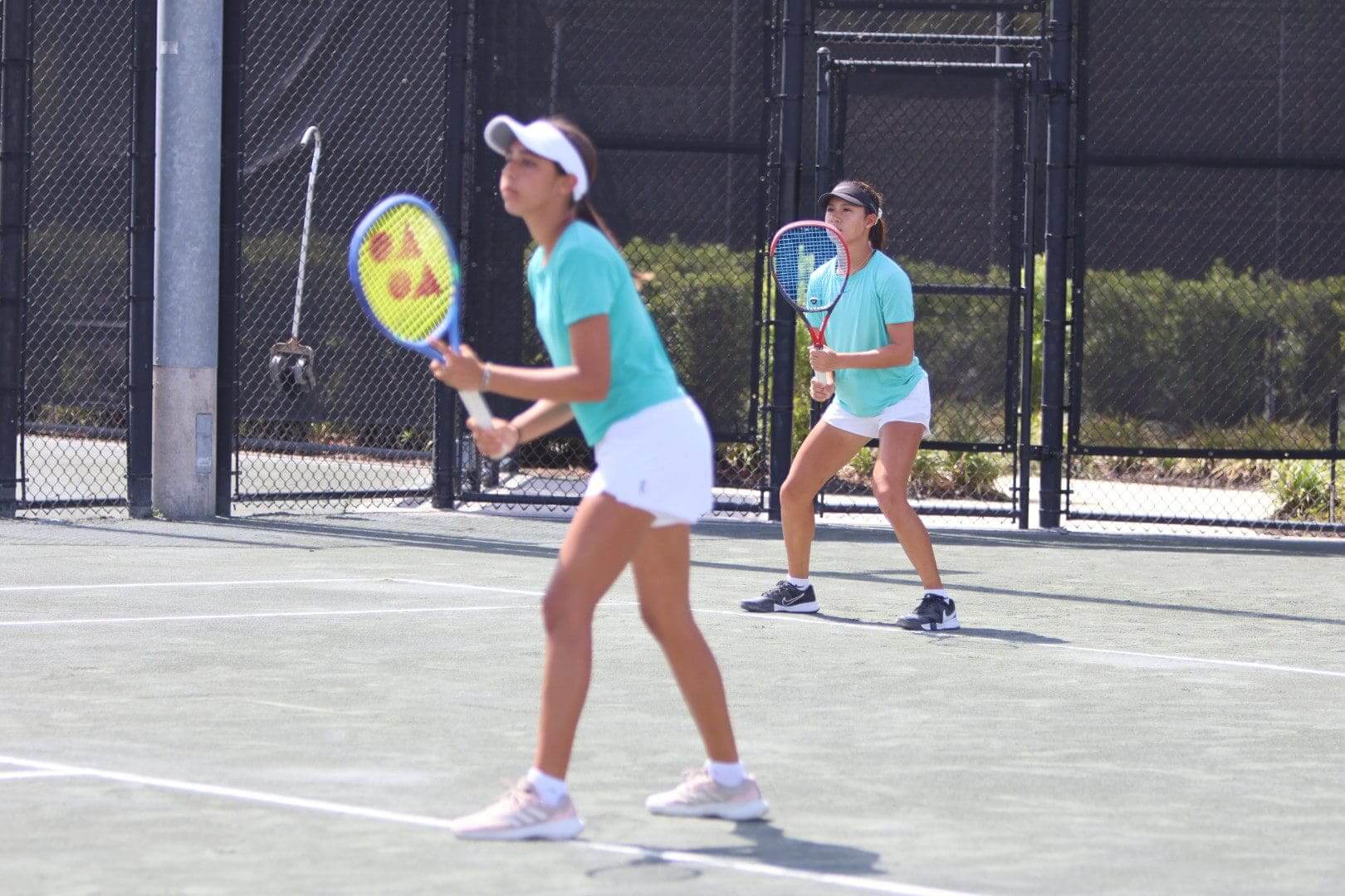 Two women playing pickleball on an outdoor court.