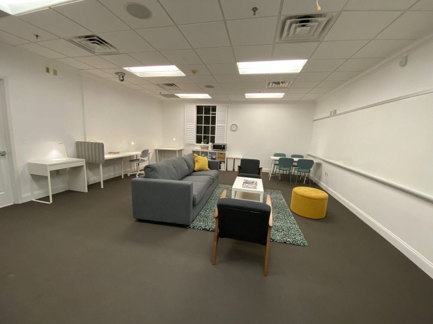Modern office lounge with sofas and a TV on the wall.