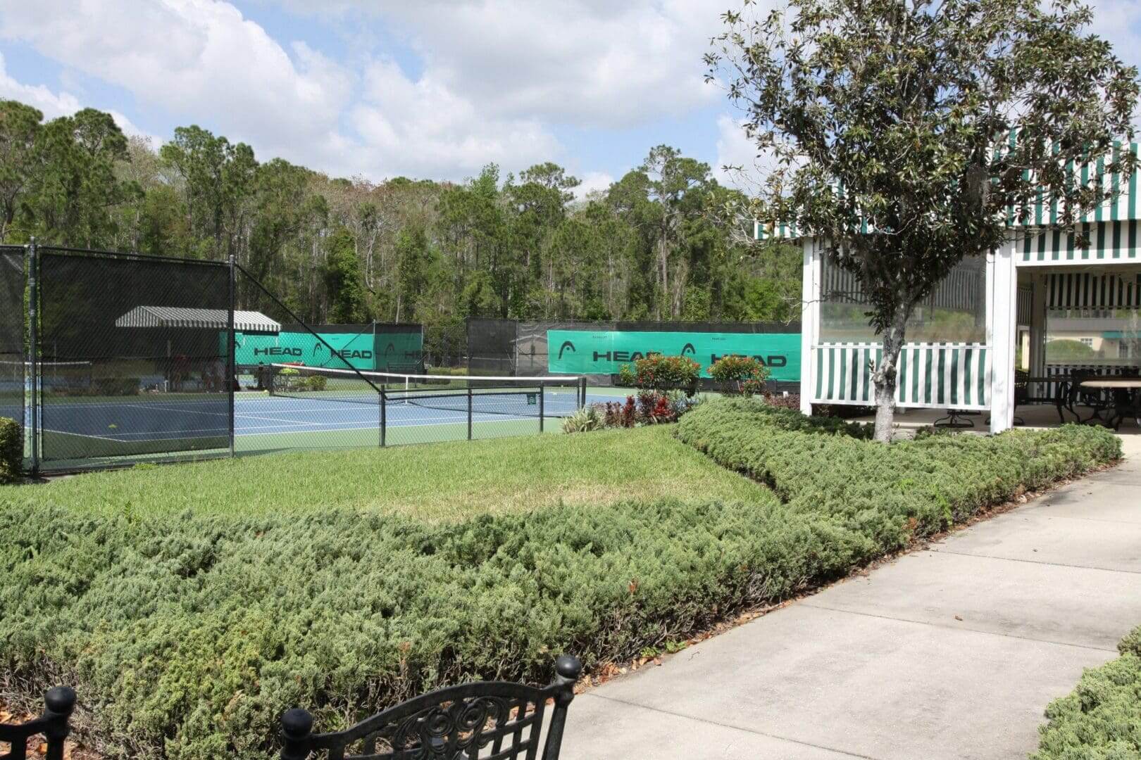 Outdoor tennis courts surrounded by greenery and trees.