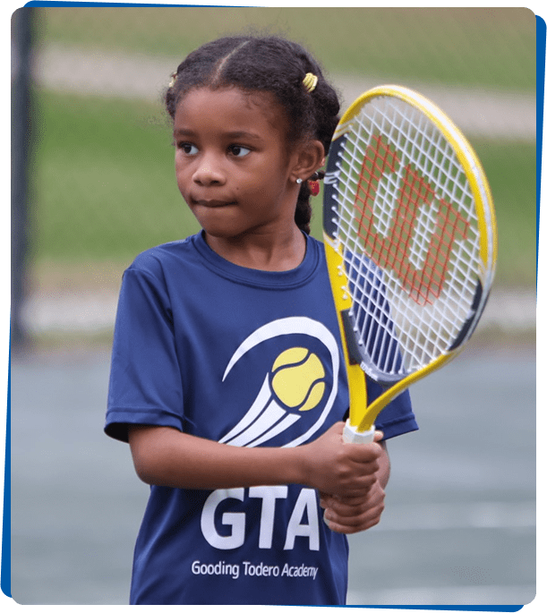 Young girl holding a tennis racket on a court.