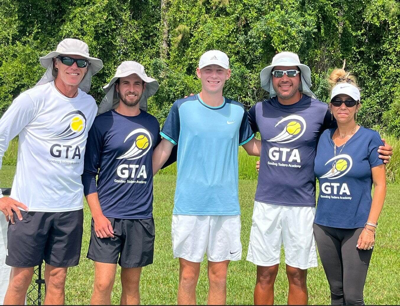 Group of people wearing tennis academy shirts.