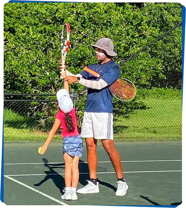 Coach adjusting girl's racket grip during lesson