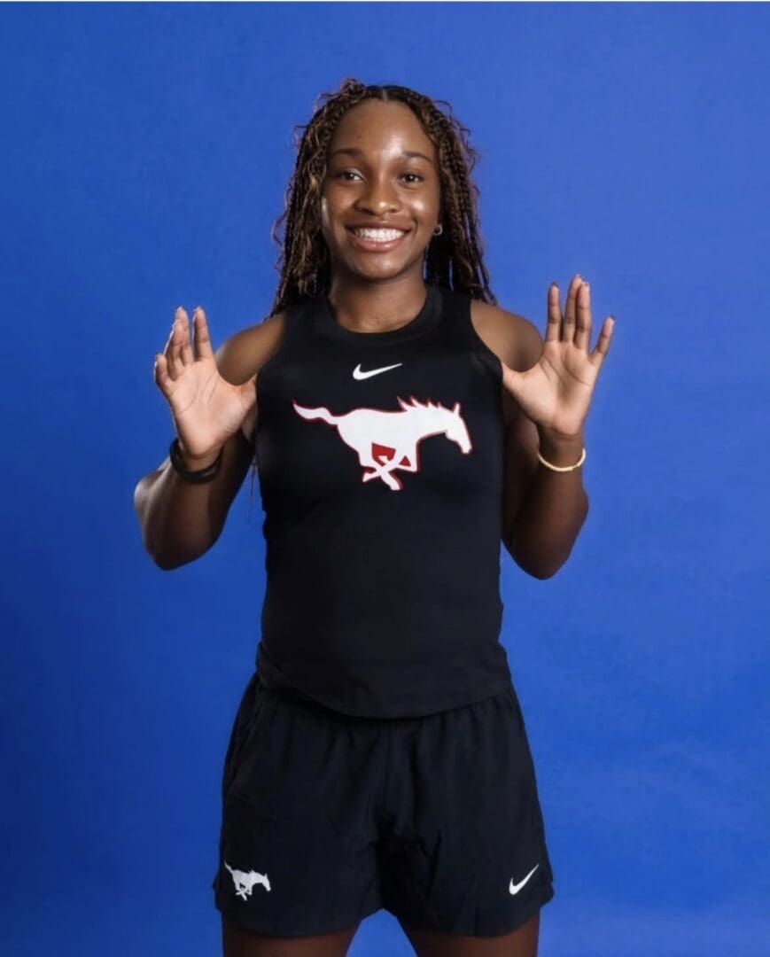 Smiling athlete in black sportswear, hands raised