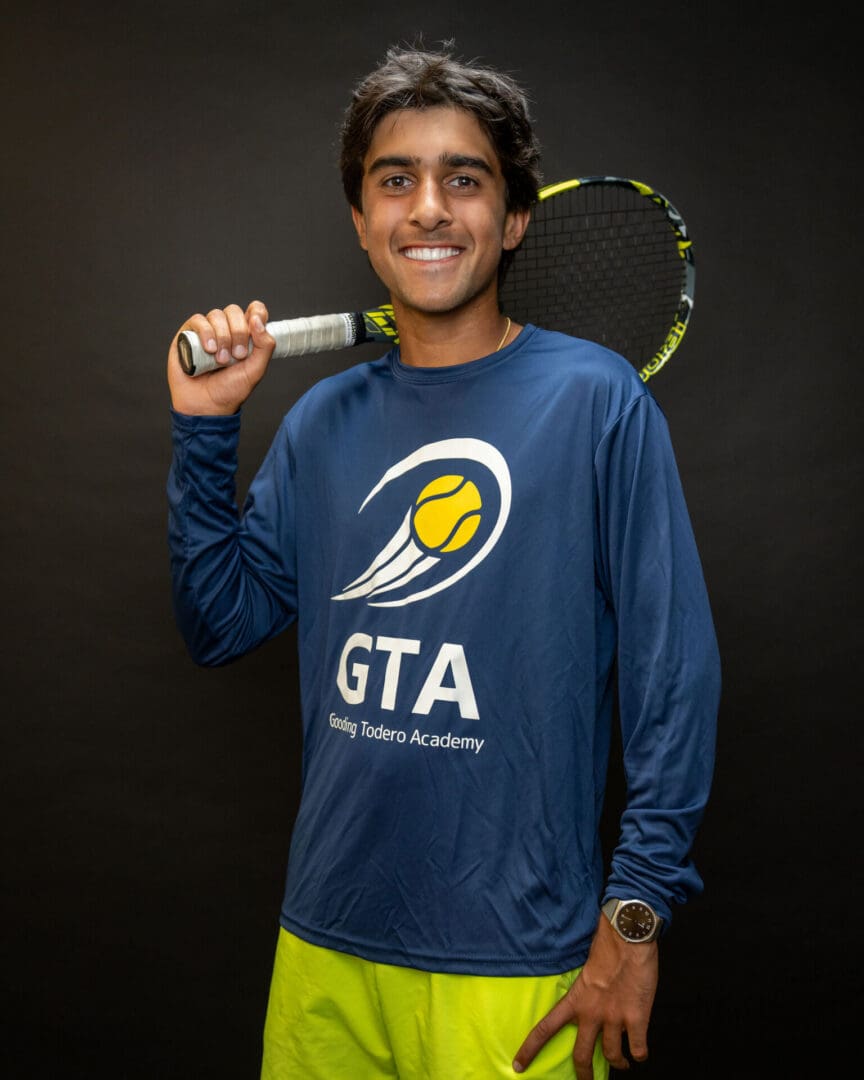 Smiling tennis player holding racket over shoulder