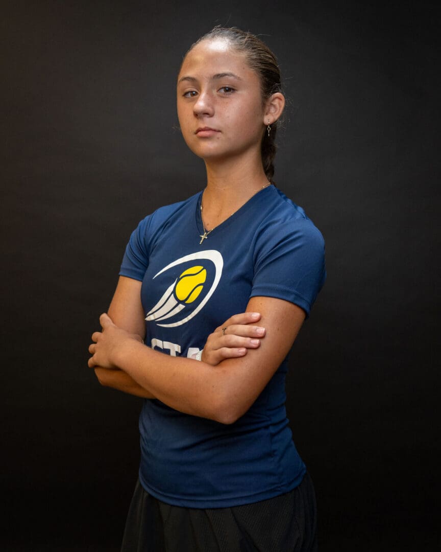Athlete in blue shirt standing with crossed arms