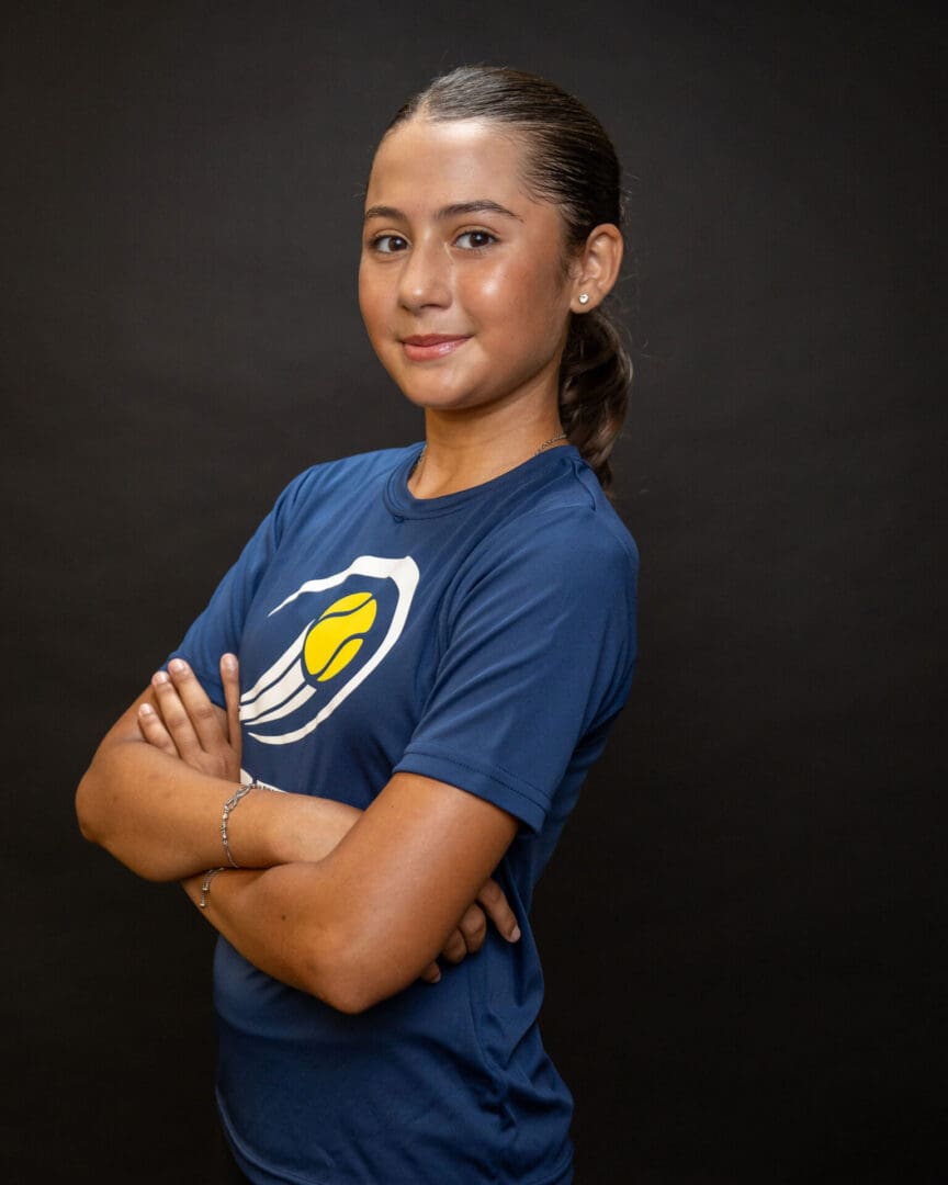 Person in blue sports shirt smiling, arms crossed